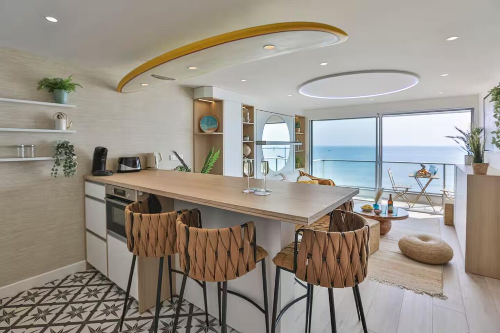 Cuisine ouverte avec comptoir dînatoire et élément décoratif fort : une planche de surf suspendue au plafond intégrant des luminaires.