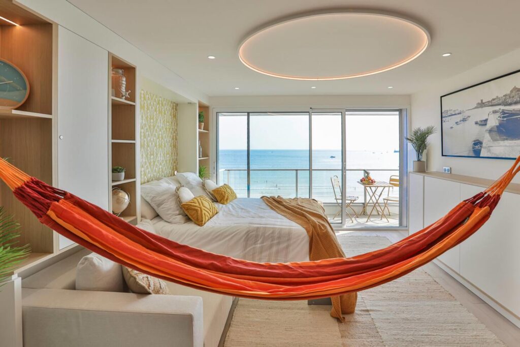 Optimisation d'un petit espace avec une armoire-lit escamotable sur mesure par Studio Vesta, décorée d'un papier peint graphique jaune, face à l'océan.