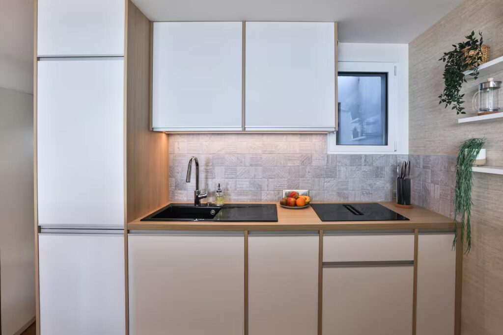 Linéaire de cuisine blanche et en bois avec une faience en pierre grise texturée et un sol géométrique esprit carreaux de ciment