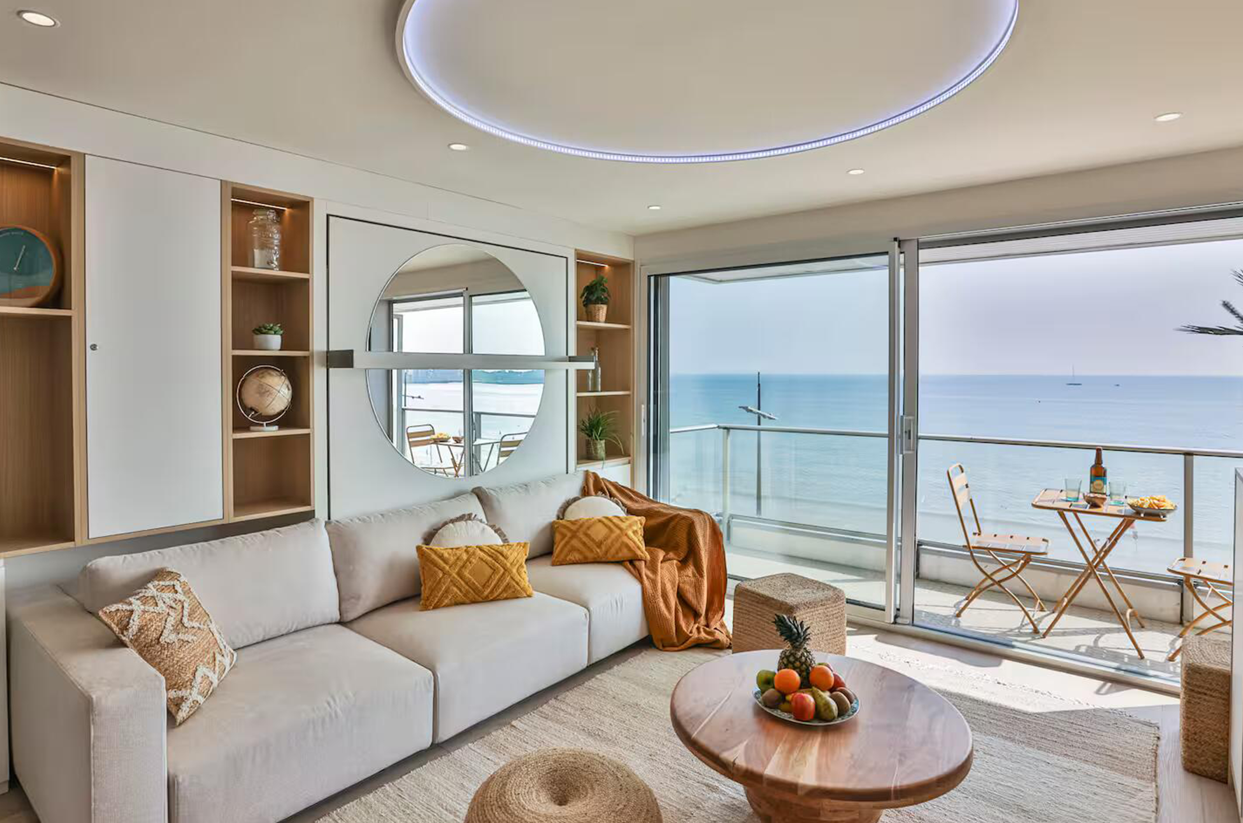 Salon contemporain avec canapé crème, table basse en bois massif et grande baie vitrée ouvrant sur l'océan aux Sables-d'Olonne.