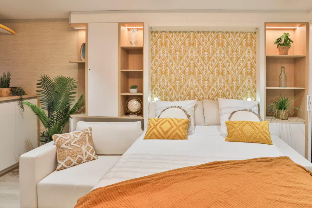 Optimisation d'un petit espace avec une armoire-lit escamotable sur mesure par Studio Vesta, décorée d'un papier peint graphique jaune, face à l'océan.