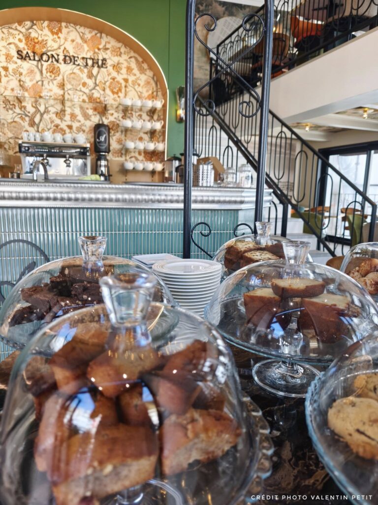 Mise en scène gourmande de gâteaux artisanaux présentés sous cloches en verre sur un comptoir en marbre prestigieux.