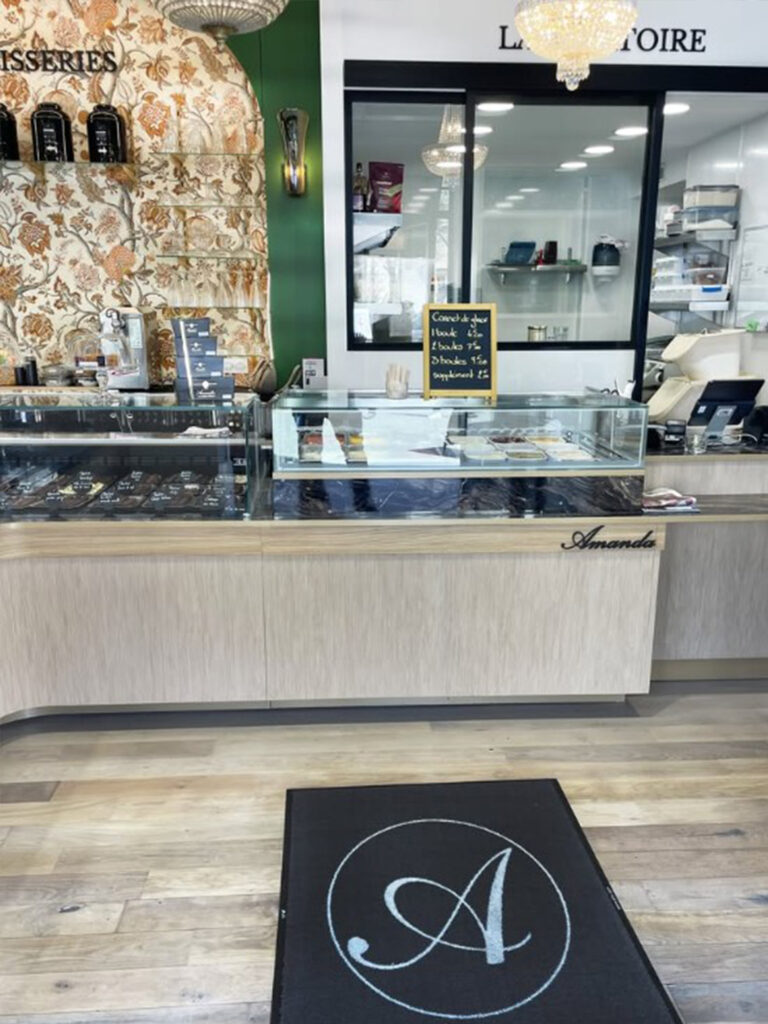 Gros plan sur les finitions soignées du mobilier en bois clair avec le logo "Amanda" en relief noir, emblème de cette institution des Sables-d'Olonne.