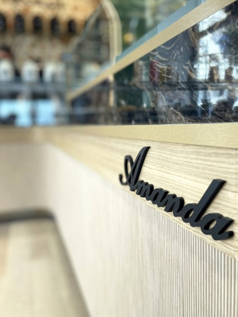 Gros plan sur les finitions soignées du mobilier en bois clair avec le logo "Amanda" en relief noir, emblème de cette institution des Sables-d'Olonne.