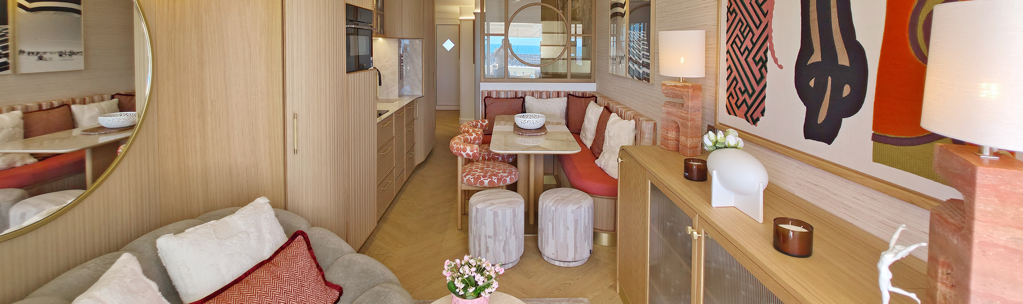 Aménagement d'un salon et espace repas sur mesure par Studio Vesta avec canapé Bubble Curve, banquette repas, verrière ouvrant sur la mezzanine et œuvre textile monumentale représentant 3 femmes, face au port de Bourgenay.