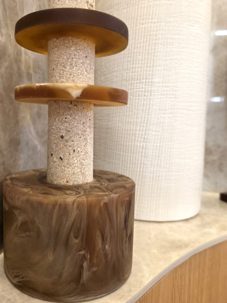 Gros plan sur une sculpture contemporaine totem associant travertin et éléments ambrés en résine.