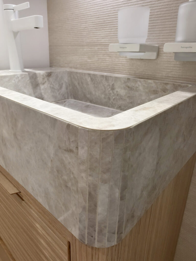 Vasque sculptée sur mesure en marbre veiné clair avec angles arrondis sur meuble en chêne par Studio Vesta.