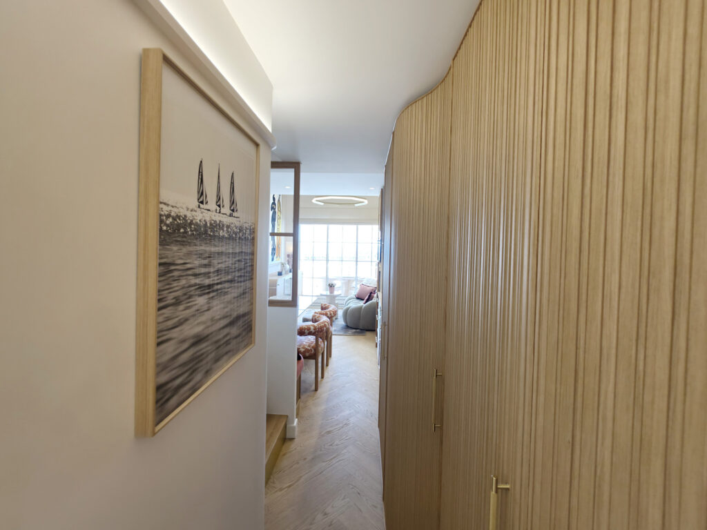 Couloir d'entrée avec grand placard habillé de tasseaux de bois, parquet en point de Hongrie et vue traversante sur le salon.