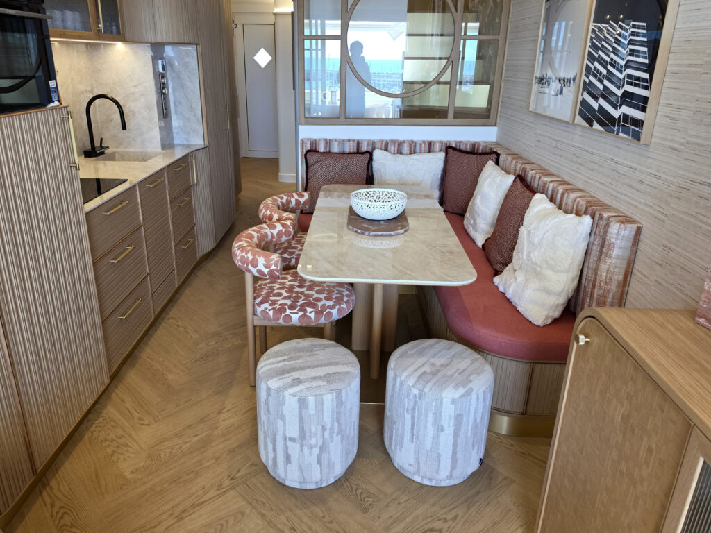 Coin repas dînatoire pour 6 personnes avec banquette sur mesure terracotta, table en marbre, chaises à motifs et poufs texturés.