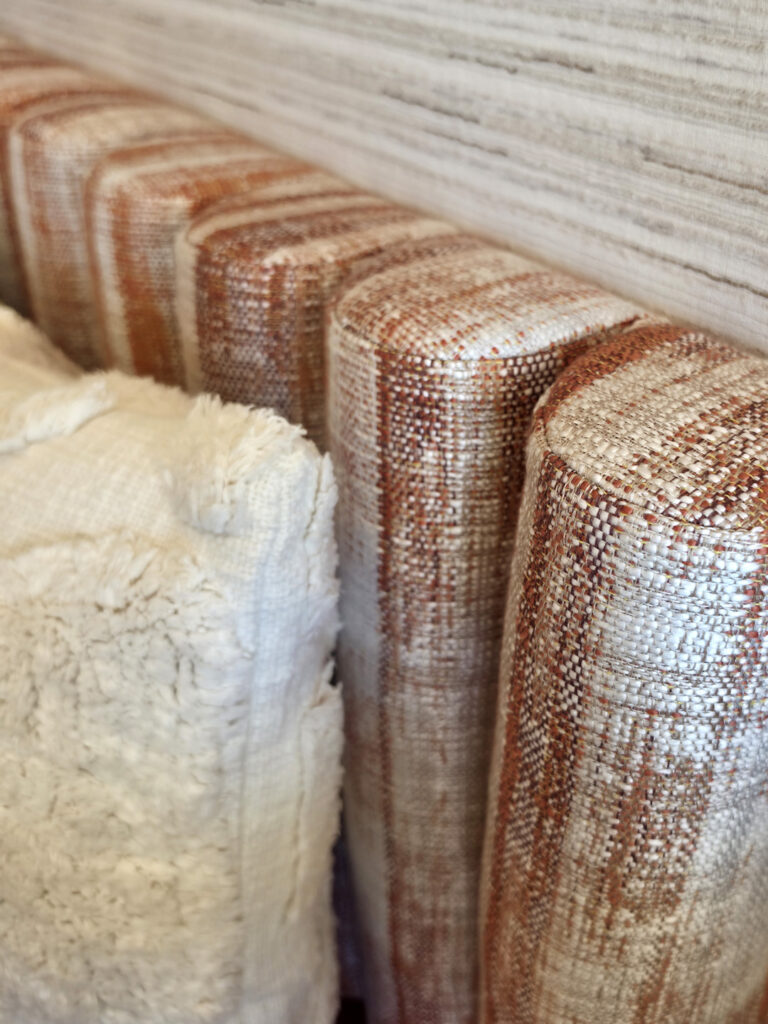 Gros plan sur le textile tressé haut de gamme de chez Pierre Frey aux teintes terracotta et crème habillant les éléments de mobilier sur mesure.