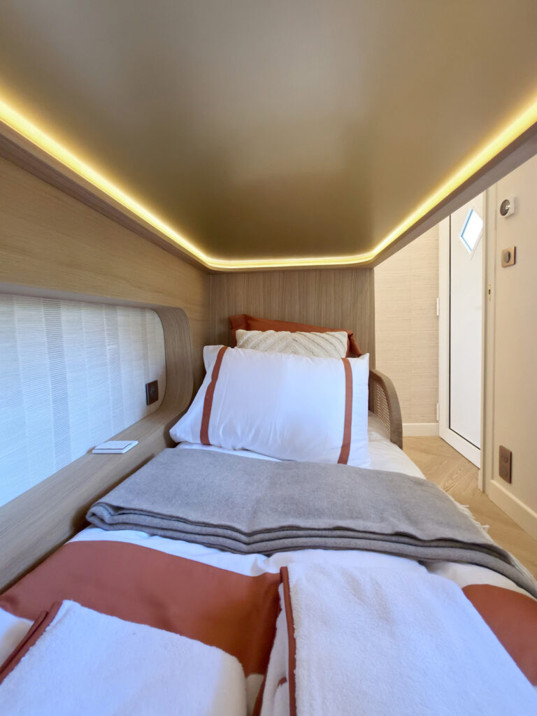 Lit superposé sur mesure en bois clair avec éclairage indirect chaleureux et linge de lit blanc et terre de sienne, rénovation Bourgenay.