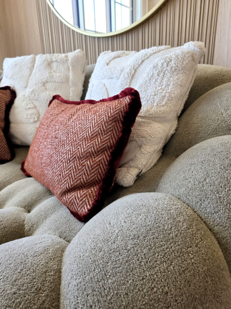 Gros plan sur la boucle textile grise du canapé Bubble Curve et coussins assortis en velours terracotta à chevrons.