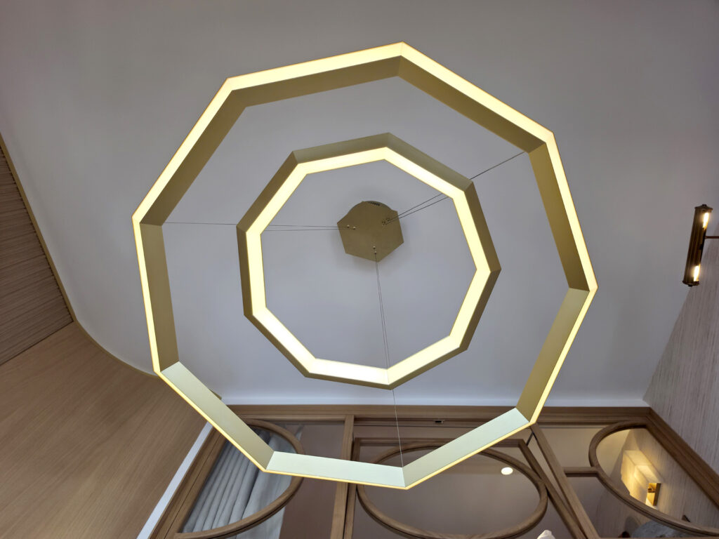 Suspension sculpturale hexagonale double anneau en laiton doré vue du dessous, avec éclairage LED intégré par Studio Vesta.