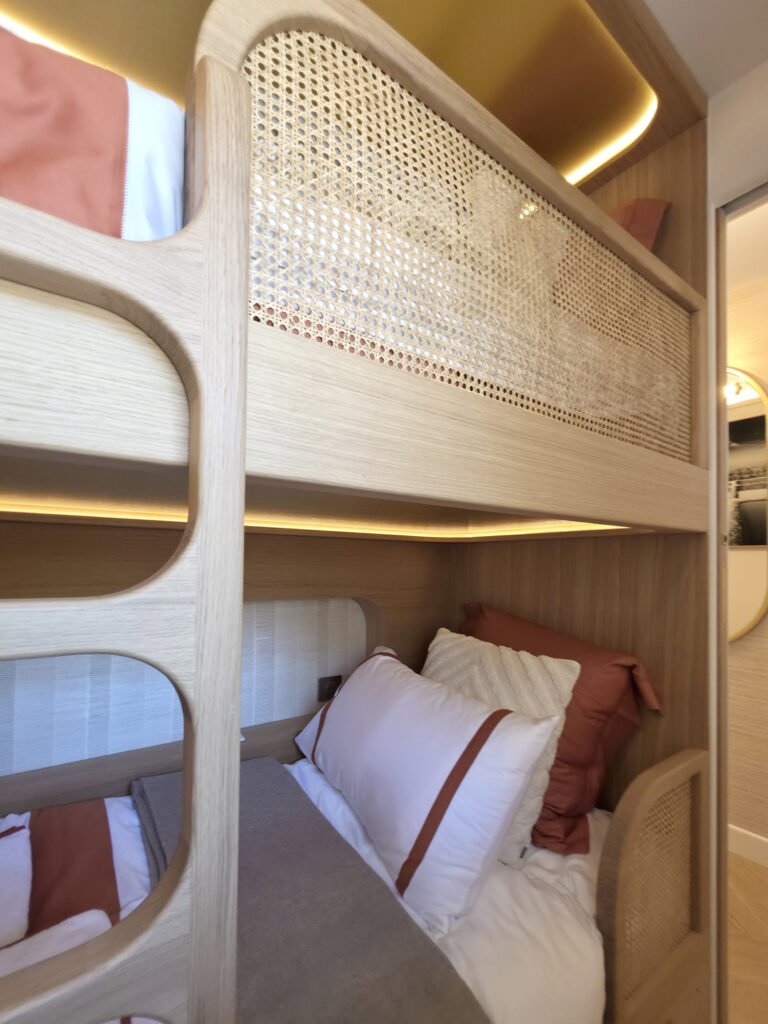Détail des garde-corps en cannage naturel et échelle intégrée sur mesure pour lits superposés en chêne par Studio Vesta.