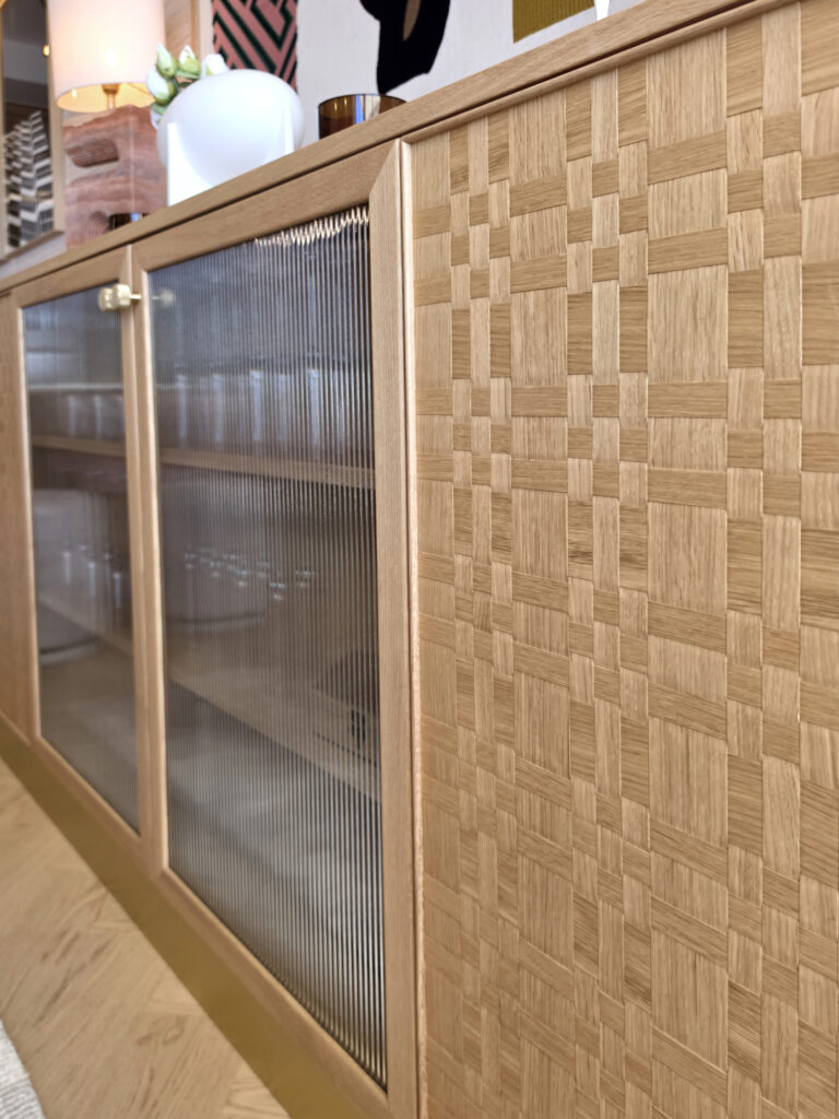 Détail du buffet bas sur mesure en chêne clair combinant portes vitrées flûtées et panneaux en bois tressé par Studio Vesta.