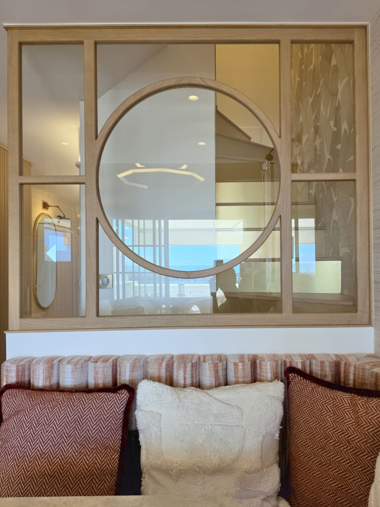 Verrière intérieure en chêne à motif circulaire géométrique surmontant le dossier de la banquette repas sur mesure.