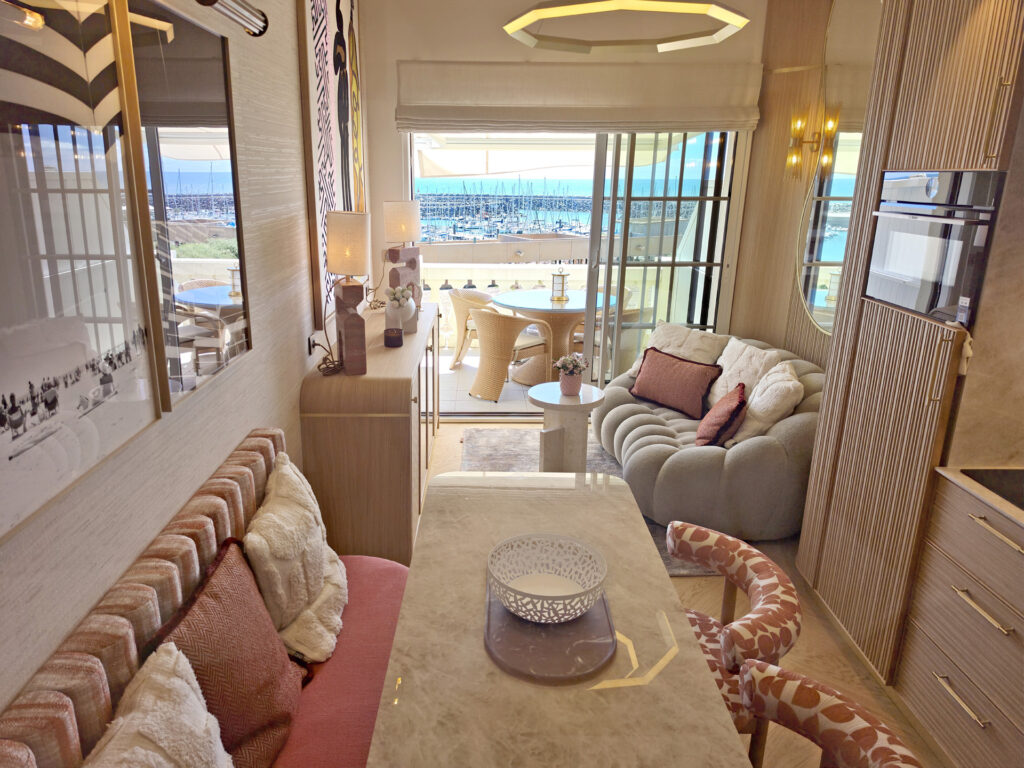 Vue en enfilade depuis l'espace repas vers le salon et la terrasse avec vue sur le port de Bourgenay.