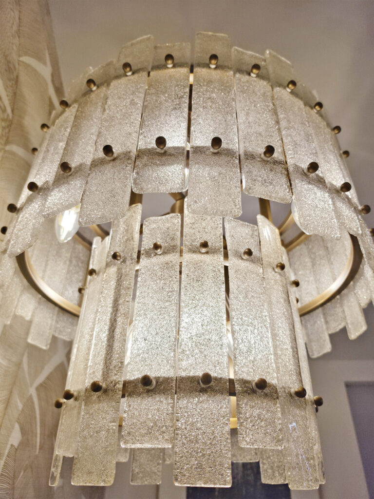 Zoom sur les plaques de verre moulé et le cerclage en laiton doré d'un lustre cascade vintage haut de gamme.