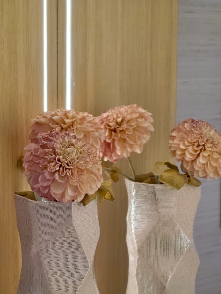 Vases en céramique blanche texturée avec dahlias roses se reflétant dans le miroir de la coiffeuse sur mesure.