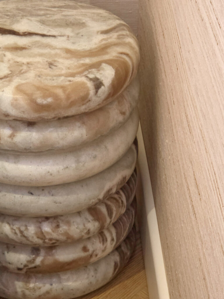 Détail d'une table de nuit sculptée en marbre naturel veiné à anneaux superposés, placée dans une niche en bois par Studio Vesta.