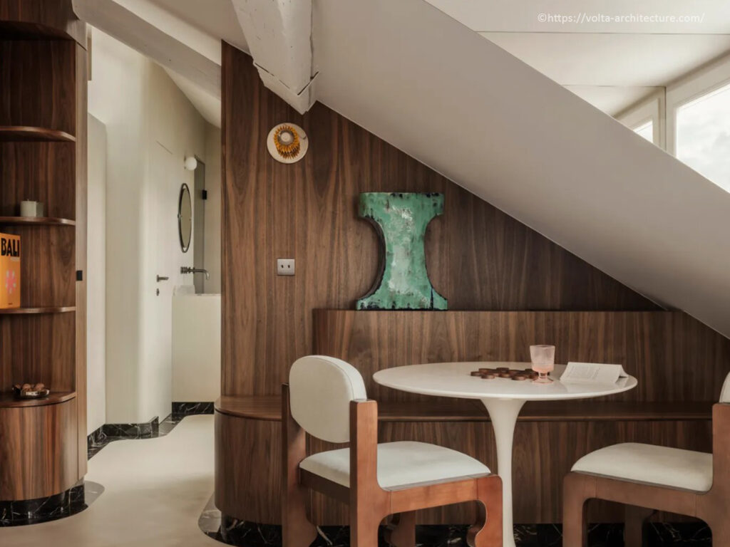 Coin repas sur mesure sous rampant avec banquette en noyer massif, table tulipe blanche et chaises design par l'Agence Volta.
