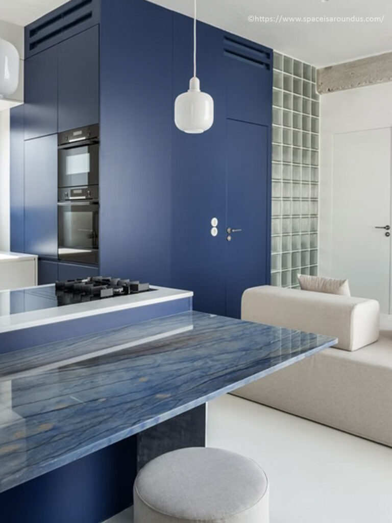 Cuisine compacte sur mesure bleu nuit avec plan de travail en marbre bleu veiné et briques de verre translucides par Space Is Around Us.