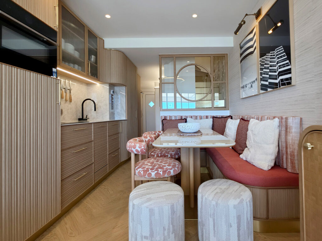 Agencement sur mesure 42 m² par Studio Vesta avec banquette d'angle terracotta, table en marbre, cuisine en bois strié et verrière cintrée.